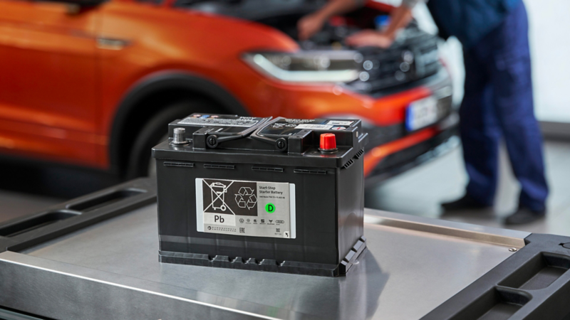 Volkswagen Genuine AGM Starter Battery on a roller container, in the background a VW T-Cross
