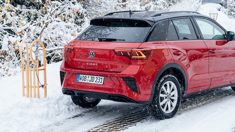 Ein Schlitten steht neben einem VW T-Roc im Schnee.