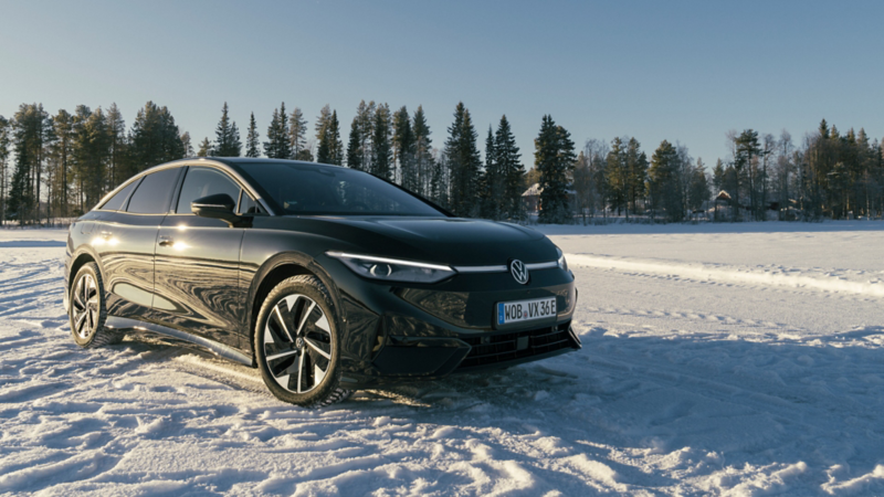 Een zwarte ID.7 staat in de sneeuw in een winters landschap in de zon. 