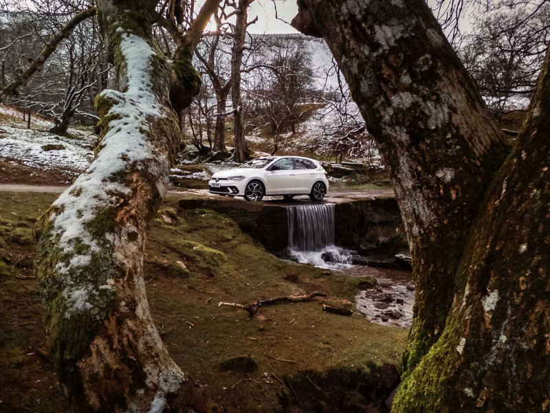 A white Polo GTI driving over a small waterfall leading into a rocky creak