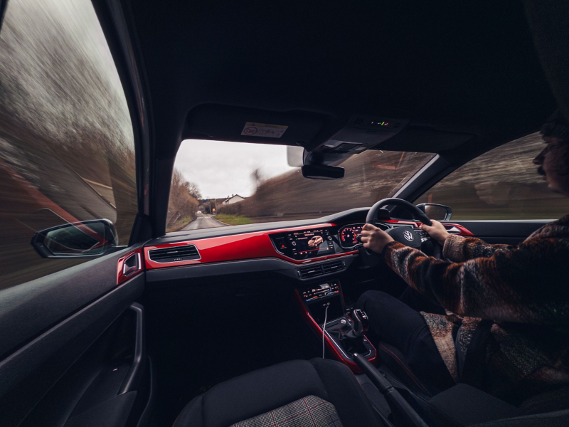 Interior view from the front passenger seat of a white Polo GTI as it drives on a mountain road