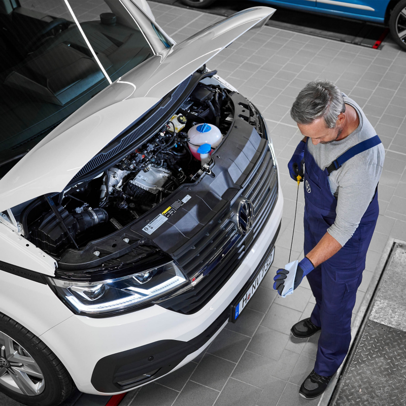 Ein Mechaniker überprüft den Motorölstand eines VW California.