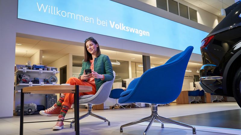 En kvinna väntar i loungen hos sin Volkswagenåterförsäljare.