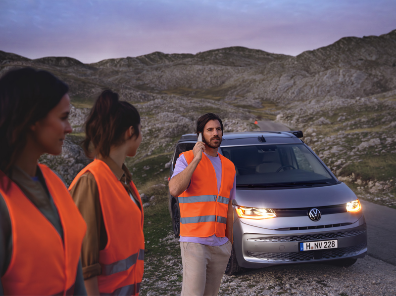 Mehrere Personen stehen in Warnwesten vor einem liegengebliebenen VW Nutzfahrzeug und rufen den Pannendienst.