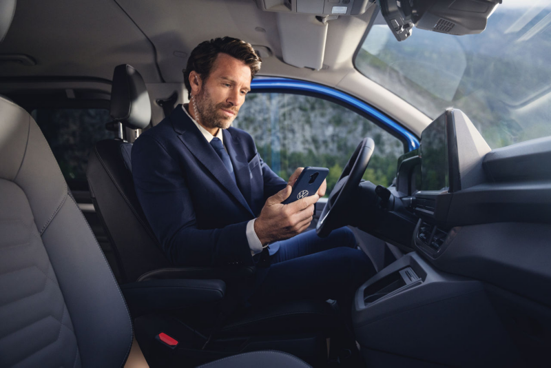 Kobieta i mężczyzna siedzą w Volkswagenie i patrzą na ekran smartfona.