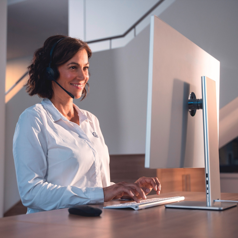 VW Servicemitarbeiterin mit Headset am Computer.