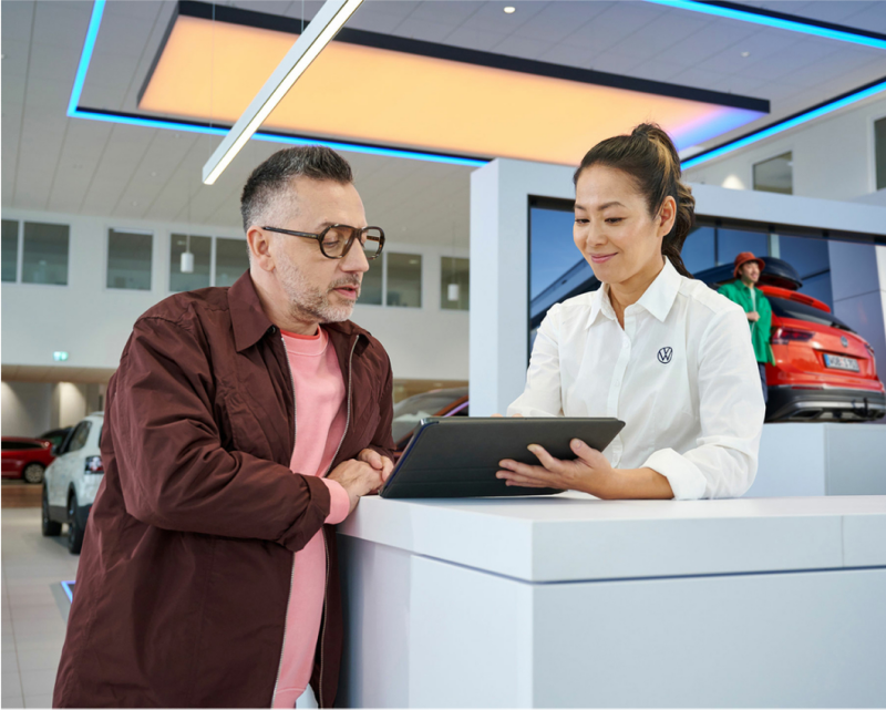 Man in VW dealership speaking with employee.