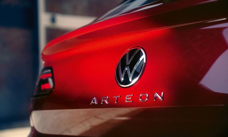 Nærbillede af den rødlakerede bagende med sølvfarvet Volkswagen logo og Arteon-modelbetegnelse.