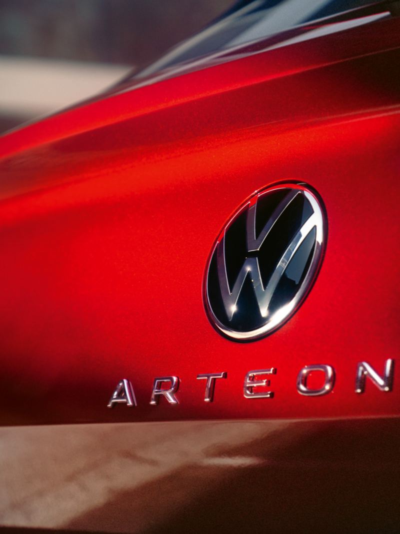 Nærbillede af den rødlakerede bagende med sølvfarvet Volkswagen logo og Arteon-modelbetegnelse.