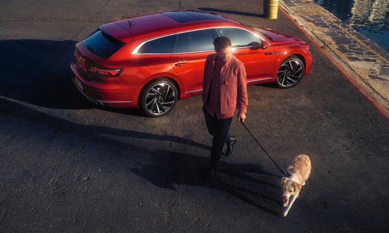 Man med hund passerar framför parkerad Arteon Shooting Brake