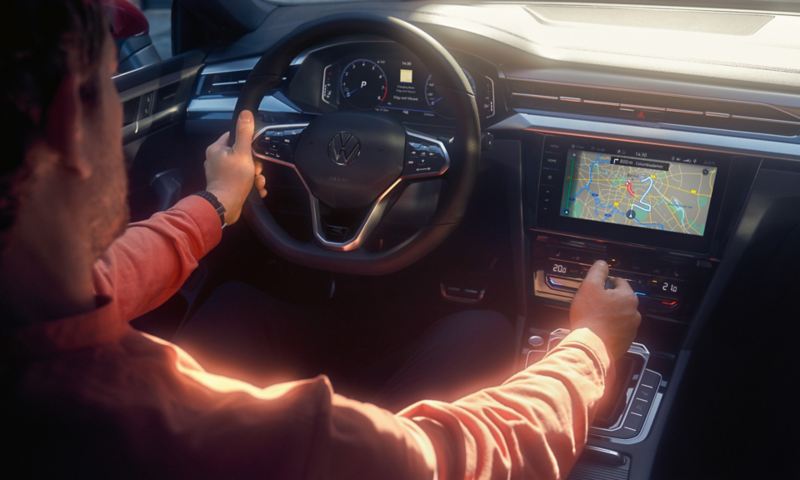 Ein Mann fährt im VW Arteon mit Multifunktionslenkrad und bedient das große Farbdisplay mit Navigationsansicht.