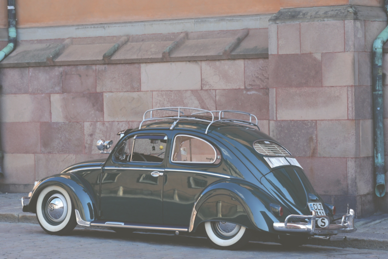 En mörkgrön Volkswagen Typ 1, även kallad Bubblan, parkerad längs en stadsgata