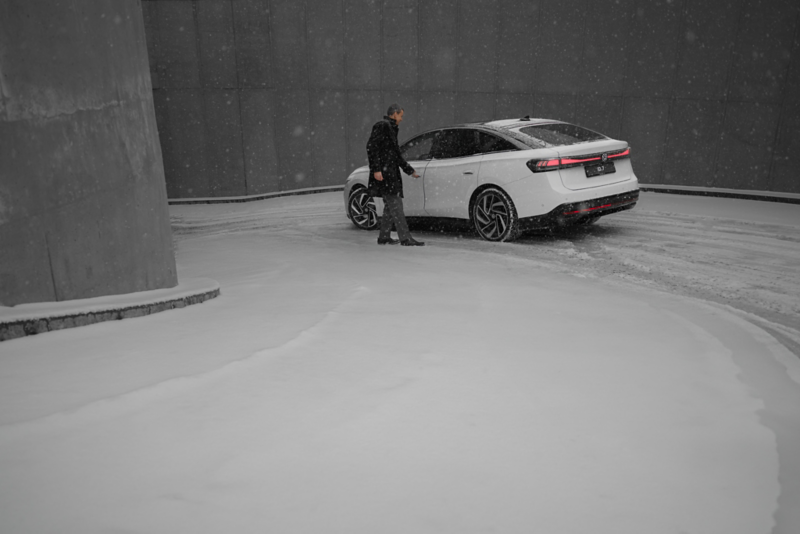 A VW ID.7 is parked on the terrace in front of a house. Side view of the vehicle.