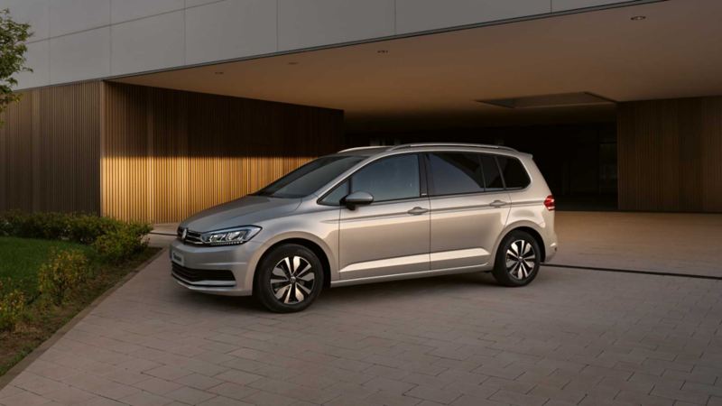 Vista laterale di una Volkswagen Touran parcheggiata davanti il garage di un'abitazione.