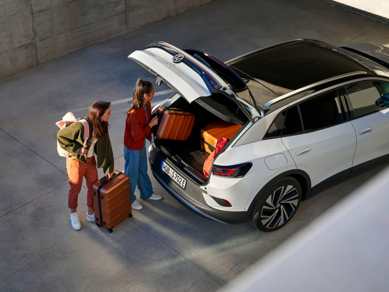 Two women load luggage compartment of VW ID.4, bags lay on luggage compartment insert with “ID.4” writing