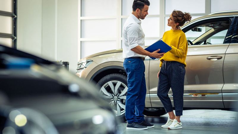 A woman and a VW service employee talking about the inspection of her car