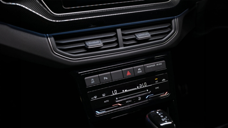 View of the centre console with screen, air conditioning and gear shift.
