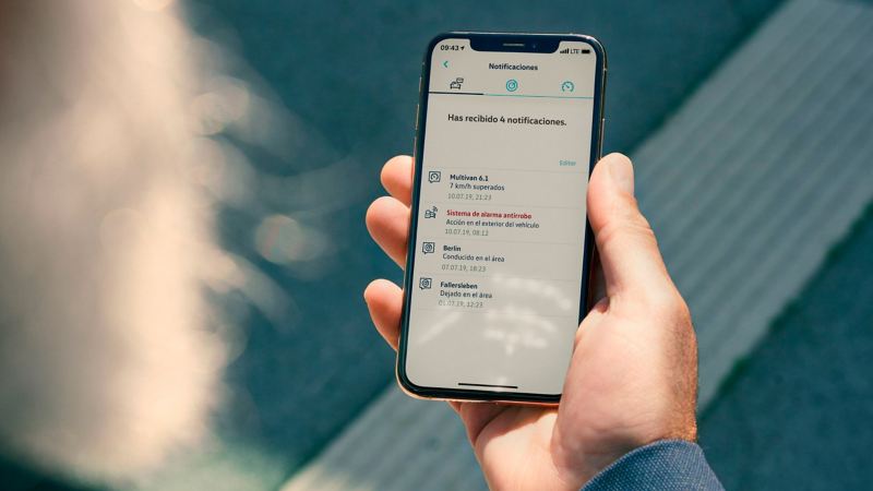 Un hombre está mirando el servicio de alarma antirrobos on-line en la aplicación de VW Connect de su smartphone.