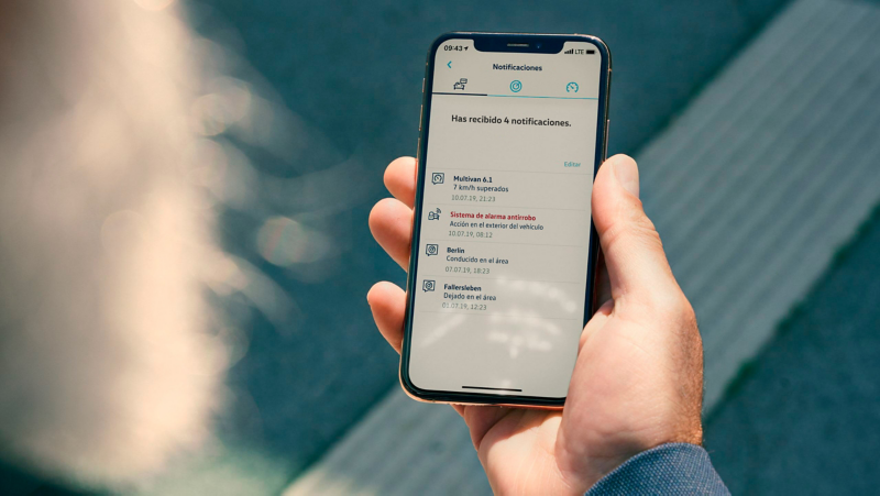 Un hombre está mirando el servicio de alarma antirrobos on-line en la aplicación de VW Connect de su smartphone.
