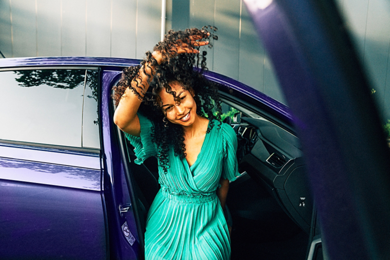 Woman smiling while sitting in blue Volkswagen.