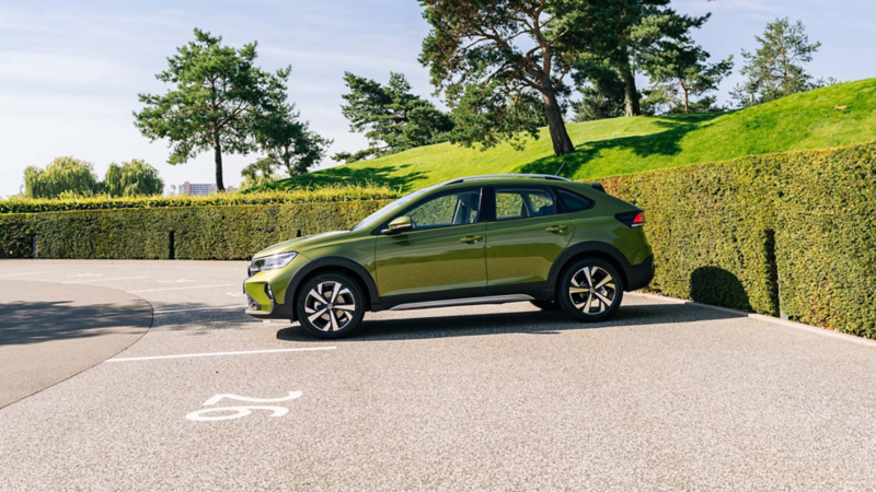 En grön Tagio parkerad på en solig parkeringsplats