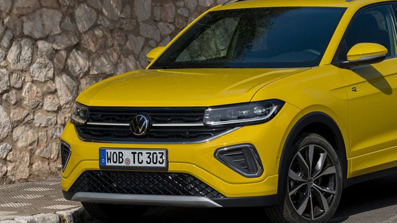 Front view of yellow T-Cross parked in front of stone wall