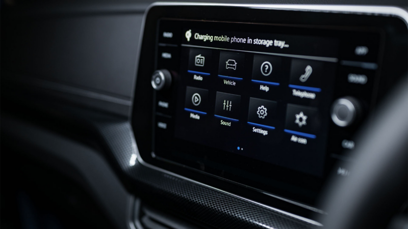 A man looks at his mobile phone in the driver’s seat with the door open.