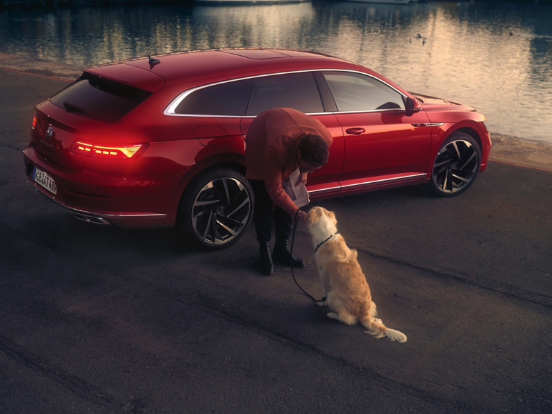 Woman petting dog with Arteon car in background
