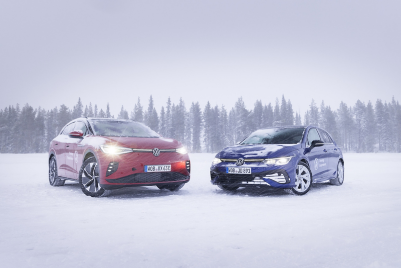 Två elbilar från Volkswagen står parkerade på ett snötäckt vinterlandskap med skog i bakgrunden