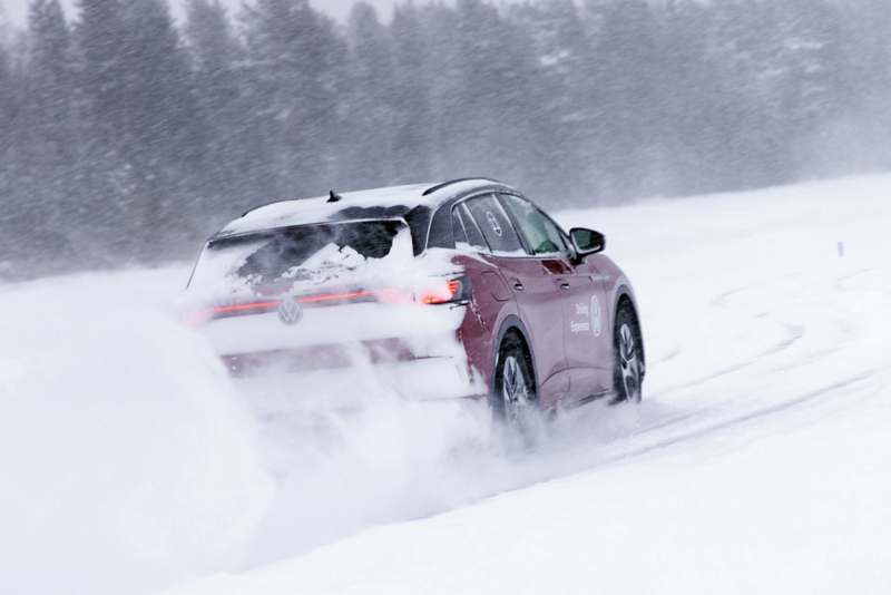 En röd Volkswagen ID.4 kör på en snötäckt isbana i vintermiljö.