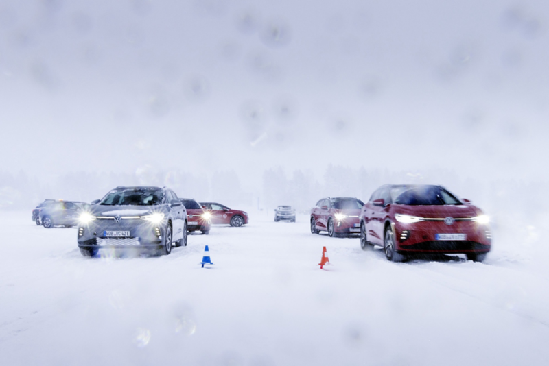 Flera bilar från Volkswagen kör på en snötäckt isbana, markerad med koner, under vinterförhållanden.