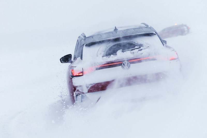 Snöklädd Volkswagen ID.4 sedd bakifrån, kör i ett vinterlandskap
