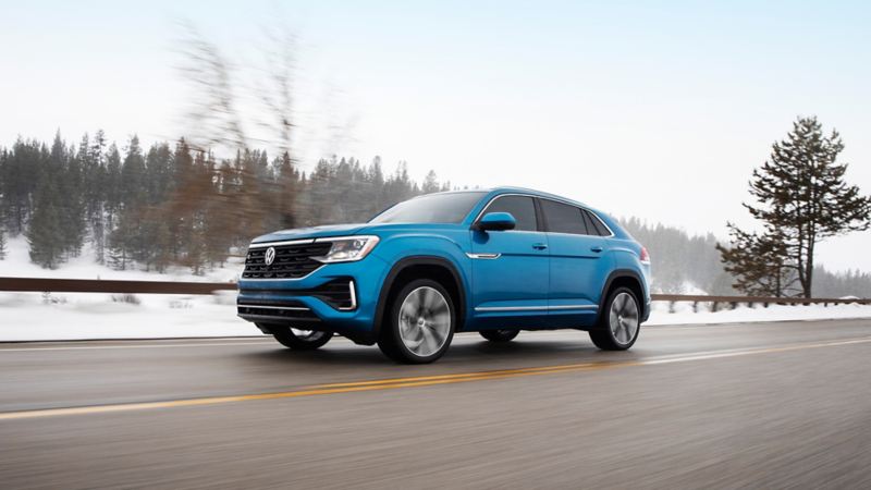 The blue 2024 Volkswagen Cross Sport driving on the highway during winter