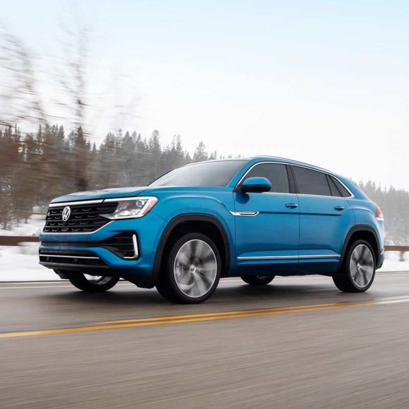 The blue 2025 Volkswagen Atlas Cross Sport driving on the highway during winter