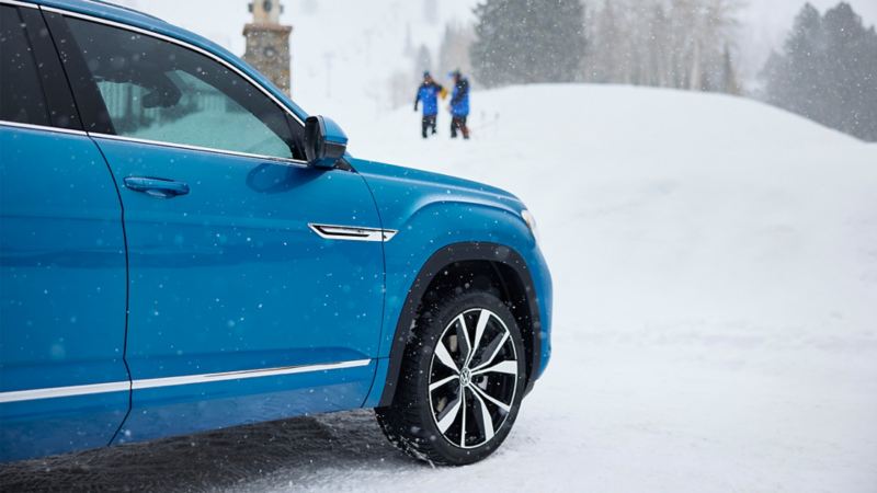 The blue 2024 Volkswagen Cross Sport parked near a snowhill