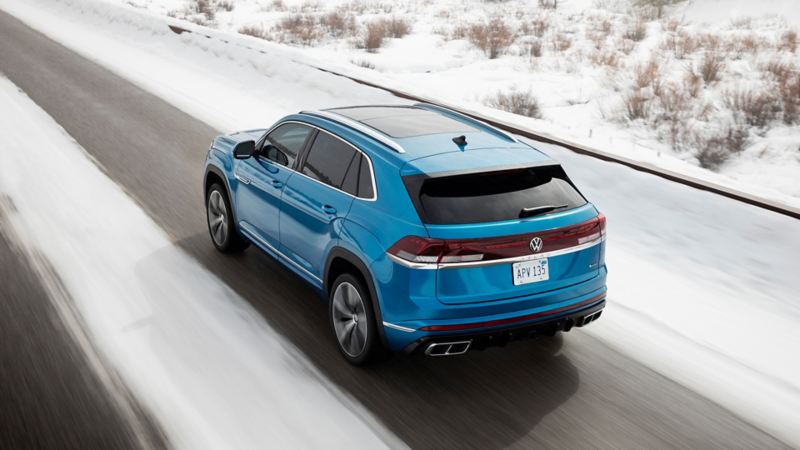 A back view of the 2024 Volkswagen Cross Sport driving on the snowy highway