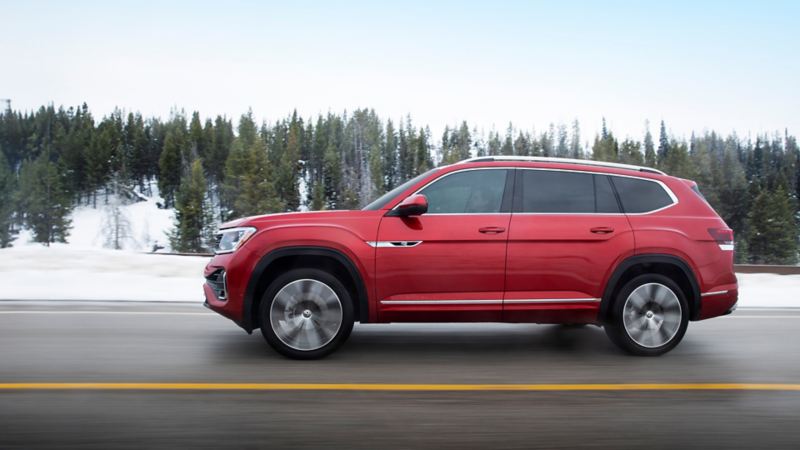 The red 2024 Volkswagen Atlas driving on the highway with a forest on the background