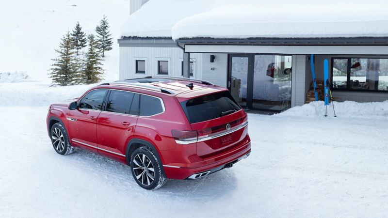 Le Volkswagen Atlas 2024 rouge garé près d’une maison en hiver