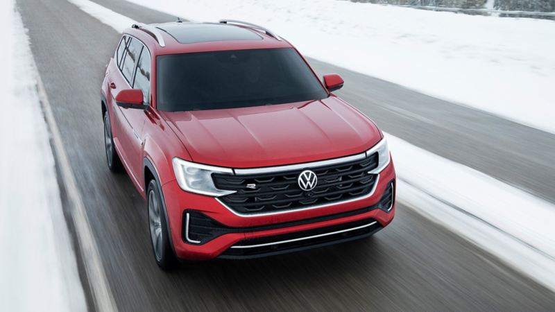 Une photo vue de face du Volkswagen Atlas 2024 rouge roulant sur l’autoroute en hiver
