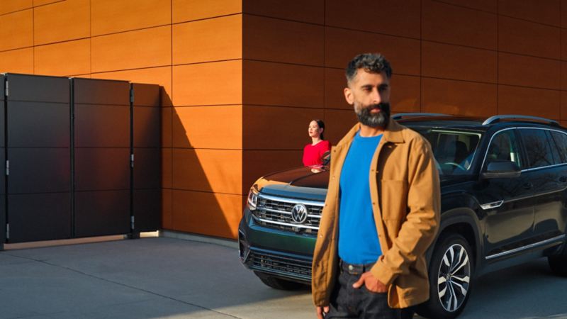 A man and woman standing next to a parked 2022 VW Atlas