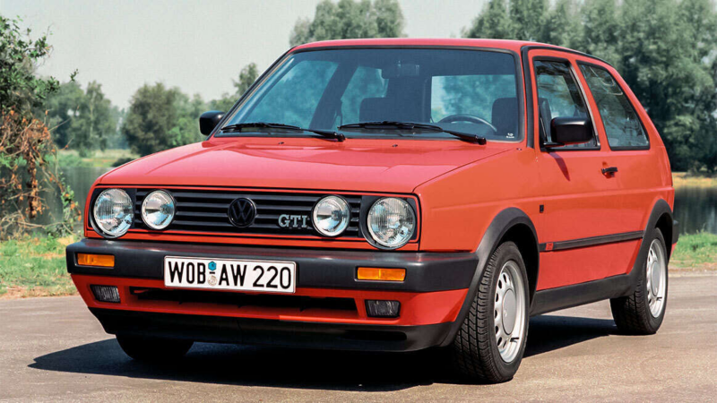 a front facing original red Golf GTI surrounded by trees