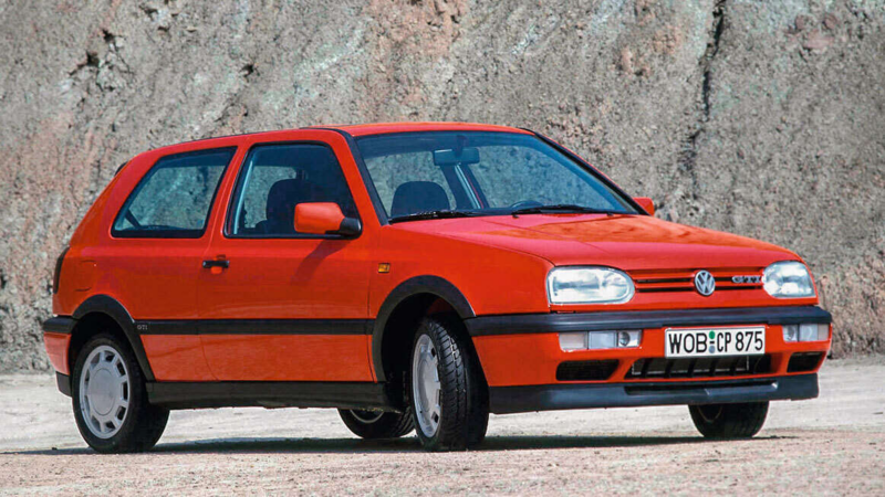 an original red Golf GTI driving outside by a cliff