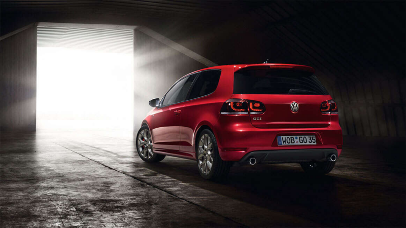 rear view of a red Golf GTI driving out of a dark garage into the sun