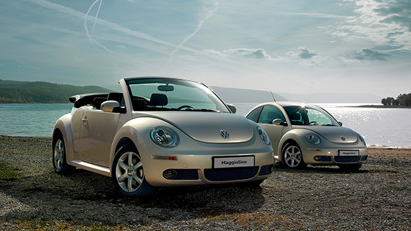 Vista 3/4 di New Beetle e New Beetle Cabriolet VW parcheggiati in una spiaggia.