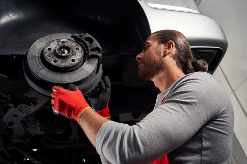 Een Volkswagen werknemer voert onderhoud uit aan de remmen van een Volkswagen voertuig