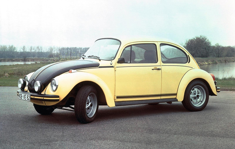 Classic yellow Volkswagen Beetle parked on a road, shown in side profile with its distinctive rounded shape and black bonnet