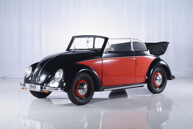 Classic red and black Volkswagen Beetle convertible displayed in a studio, highlighting its 1949 design and iconic curves.