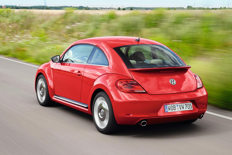 Volkswagen Beetle in red seen from the rear while driving, highlighting its rounded design and compact shape