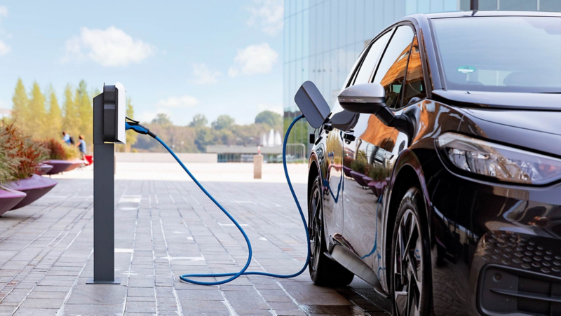 Een Volkswagen wordt opgeladen bij een laadpaal op een bedrijventerrein