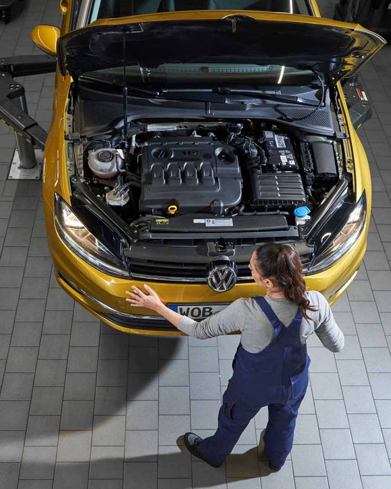 Un meccanico di Volkswagen Service ispeziona il motore di un'auto VW.